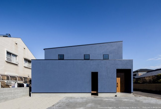 紺色の外壁に包まれた木のドアの家